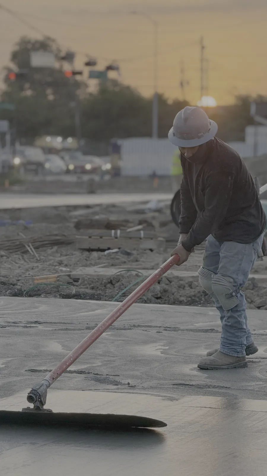 Crew member bull-floating fresh concrete on a Houston commercial slab